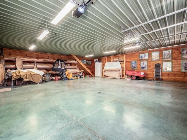 garage featuring wooden walls, water heater, white fridge, and a garage door opener