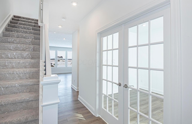 interior space with baseboards, wood finished floors, recessed lighting, stairway, and french doors