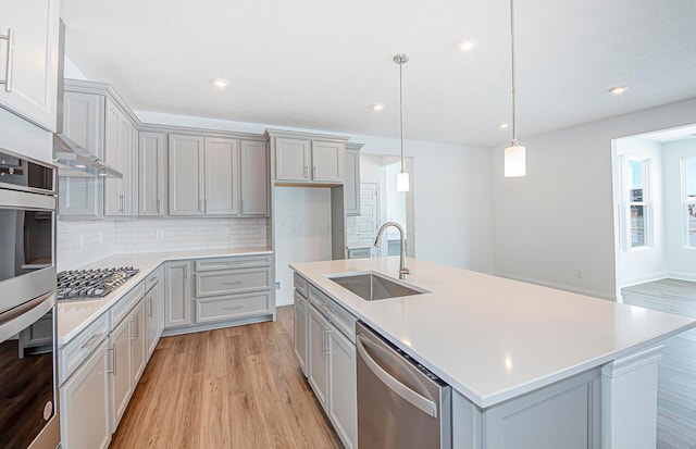 kitchen with a sink, appliances with stainless steel finishes, gray cabinetry, and light wood-type flooring