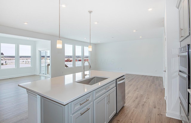 kitchen featuring open floor plan, a sink, dishwasher, and light wood-type flooring