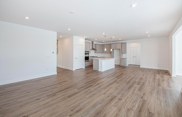 unfurnished living room featuring baseboards, light wood finished floors, and recessed lighting