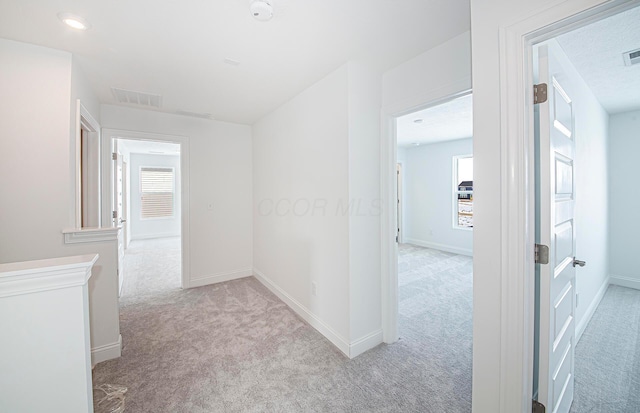 hall with carpet floors, baseboards, visible vents, and recessed lighting