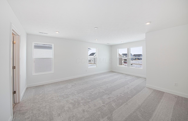 empty room featuring light colored carpet, visible vents, recessed lighting, and baseboards