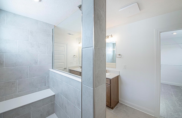 bathroom with a spacious closet, a textured ceiling, a walk in shower, and vanity