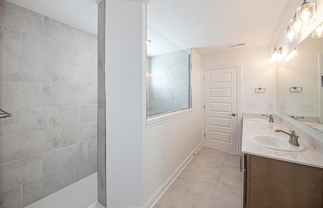 full bathroom with a sink, a textured ceiling, visible vents, and a walk in shower
