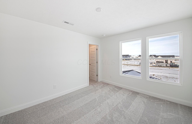 empty room featuring baseboards, light colored carpet, and visible vents