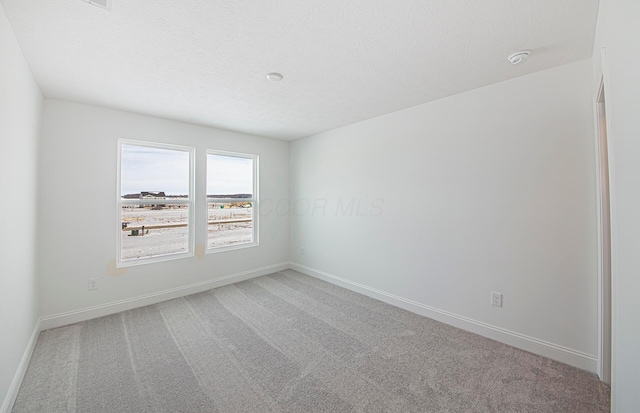 unfurnished room featuring baseboards, carpet floors, and a textured ceiling