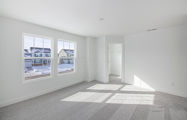 unfurnished room with baseboards, visible vents, and light carpet