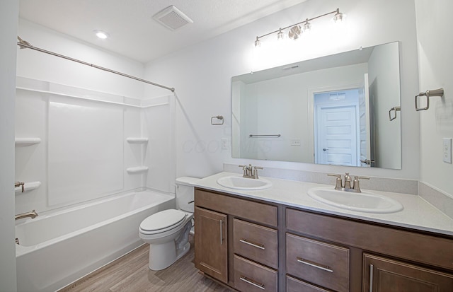 full bath featuring visible vents, a sink, double vanity, and wood finished floors