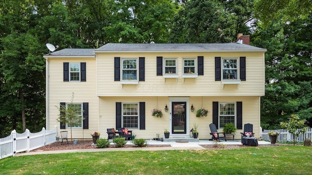 colonial-style house with a patio and a front yard