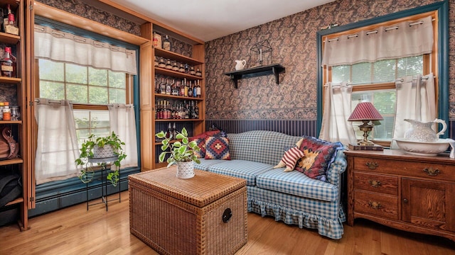 living area with built in shelves, a baseboard heating unit, and light hardwood / wood-style flooring