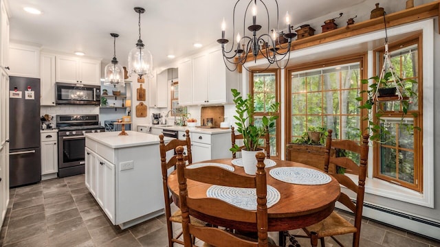 kitchen featuring white cabinets, baseboard heating, decorative light fixtures, a kitchen island, and stainless steel appliances