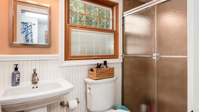 bathroom with toilet, a shower with shower door, and sink