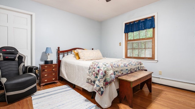 bedroom featuring hardwood / wood-style flooring, a baseboard radiator, and ceiling fan