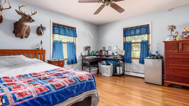 bedroom featuring ceiling fan, light hardwood / wood-style flooring, and a baseboard radiator