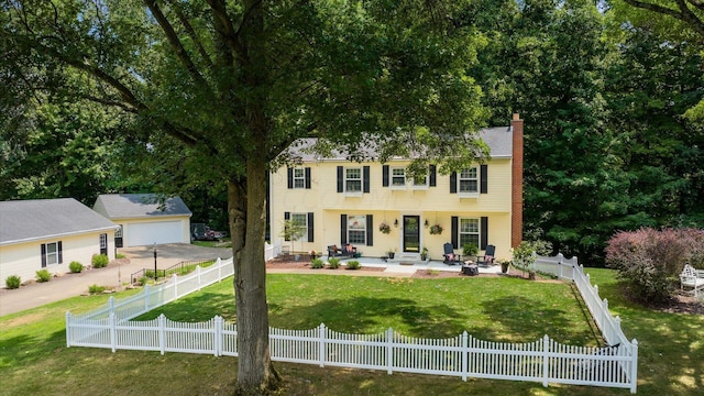 colonial inspired home featuring a patio area and a front yard