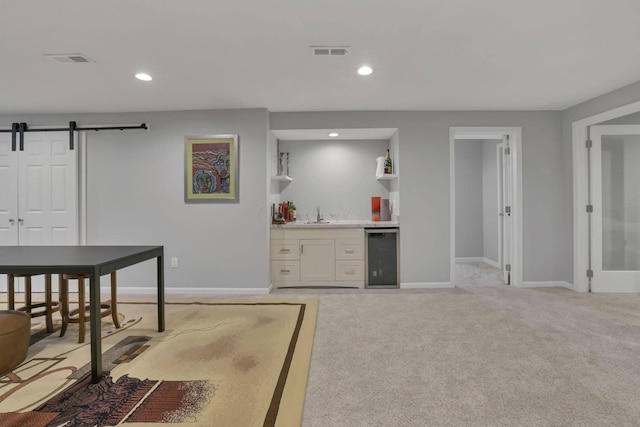 interior space with bar, light carpet, beverage cooler, and a barn door