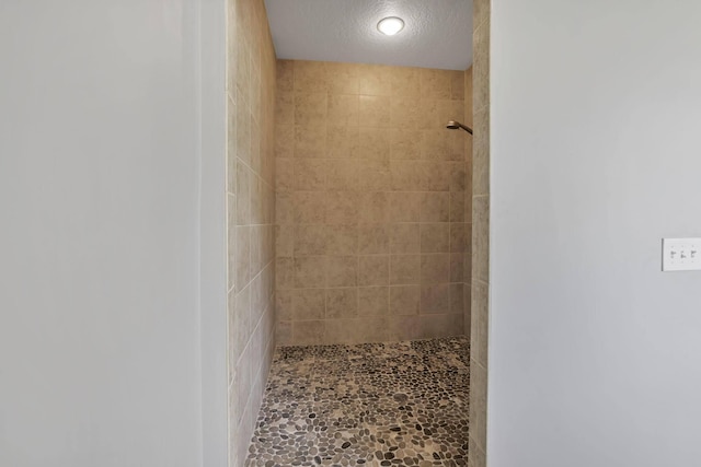 bathroom featuring a tile shower and a textured ceiling