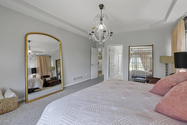 carpeted bedroom with connected bathroom, a tray ceiling, and a notable chandelier