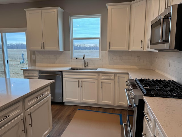 kitchen with tasteful backsplash, white cabinetry, sink, and appliances with stainless steel finishes