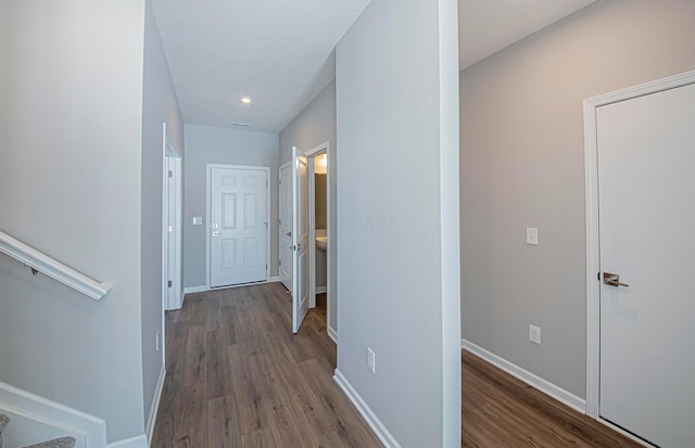 hall with a textured ceiling and wood-type flooring