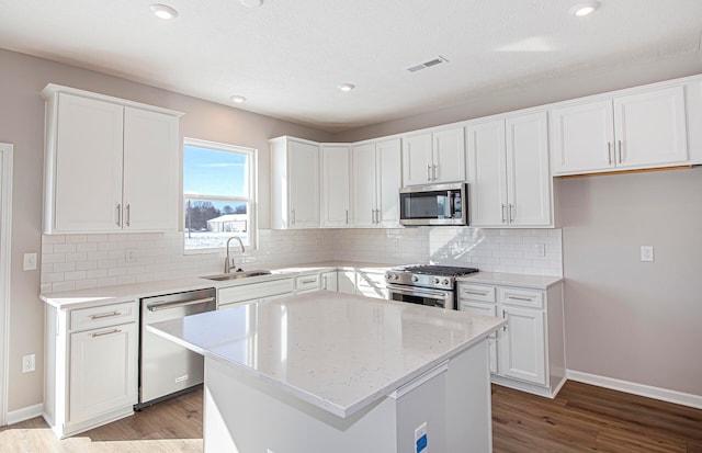 kitchen with a center island, appliances with stainless steel finishes, white cabinetry, and sink