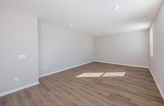 empty room featuring wood-type flooring and a textured ceiling