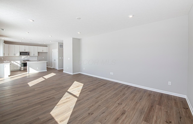 unfurnished living room featuring sink and dark hardwood / wood-style floors