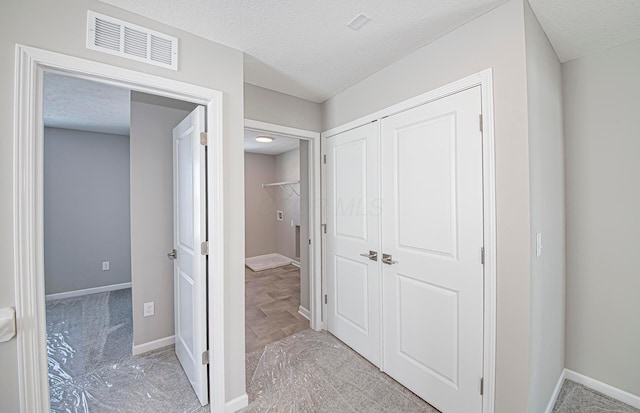 hallway featuring light carpet and a textured ceiling