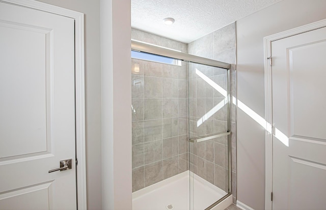 bathroom with a textured ceiling and a shower with shower door