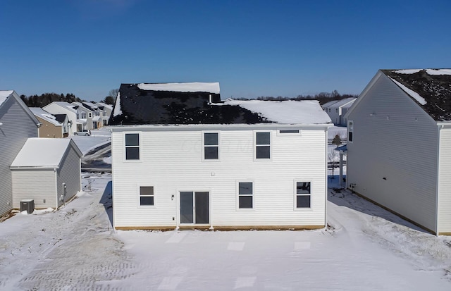 snow covered back of property featuring central AC