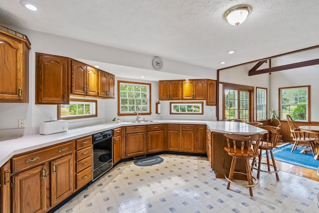 kitchen with a breakfast bar, sink, vaulted ceiling, a textured ceiling, and kitchen peninsula