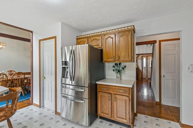 kitchen with stainless steel fridge, a textured ceiling, and light parquet floors