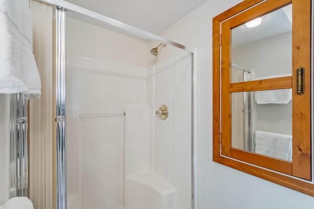 bathroom with a shower with shower door and a textured ceiling