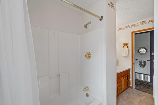 bathroom featuring tile patterned floors, vanity, washtub / shower combination, and a textured ceiling