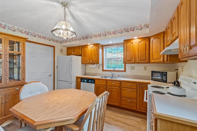 kitchen with sink, a chandelier, decorative light fixtures, light hardwood / wood-style floors, and white appliances