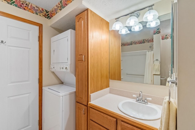 bathroom with a shower with curtain, vanity, stacked washing maching and dryer, and a textured ceiling