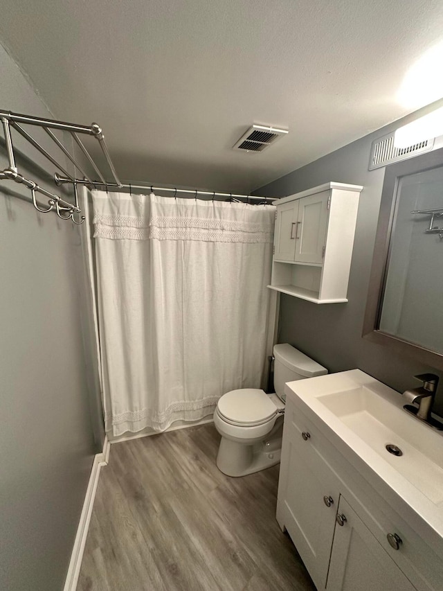 full bathroom with hardwood / wood-style floors, vanity, toilet, a textured ceiling, and shower / tub combo