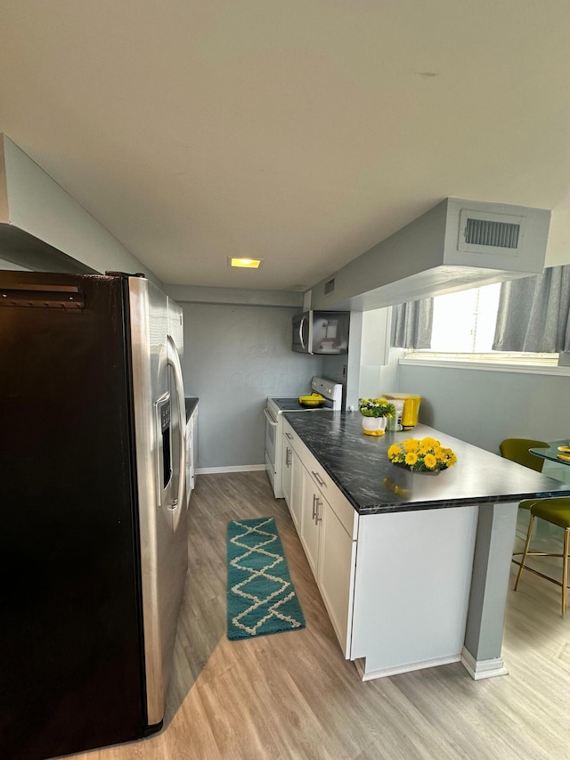 kitchen featuring kitchen peninsula, light hardwood / wood-style flooring, white cabinets, and stainless steel appliances