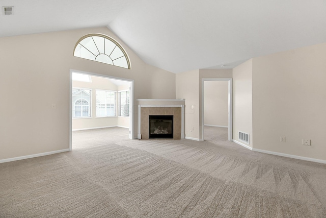 unfurnished living room with a tiled fireplace, light carpet, and vaulted ceiling