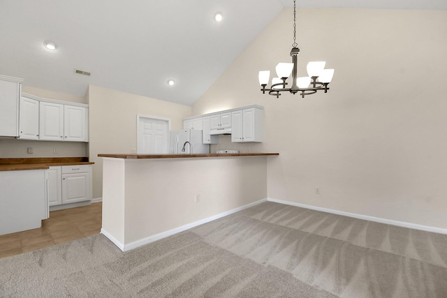 kitchen featuring kitchen peninsula, white cabinetry, white fridge, and pendant lighting