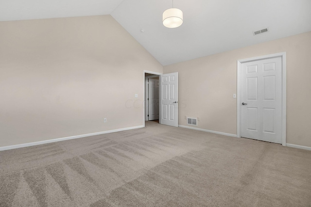 carpeted empty room with high vaulted ceiling