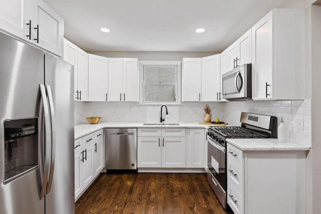 kitchen featuring dark wood-type flooring, white cabinets, sink, light stone countertops, and appliances with stainless steel finishes