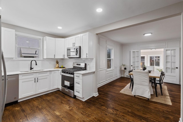 kitchen featuring appliances with stainless steel finishes, dark hardwood / wood-style flooring, backsplash, sink, and white cabinets