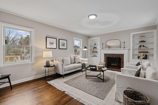 living room with crown molding, a fireplace, dark wood-type flooring, and built in features