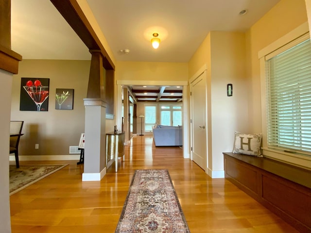 corridor featuring beamed ceiling, light wood-type flooring, and coffered ceiling