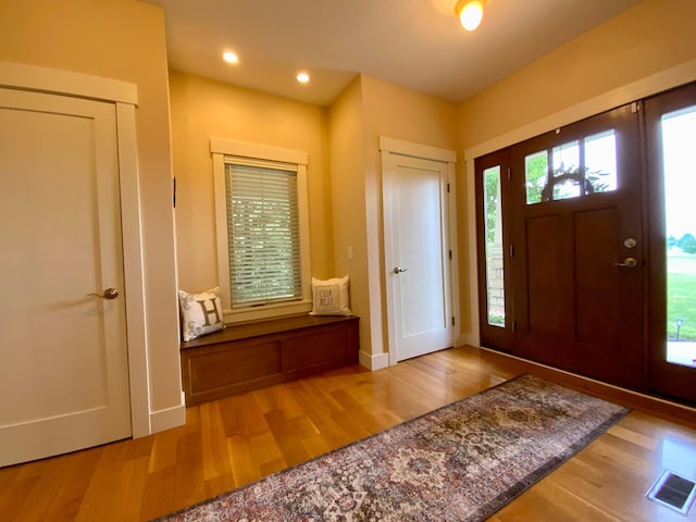 foyer featuring light wood finished floors, baseboards, visible vents, and recessed lighting