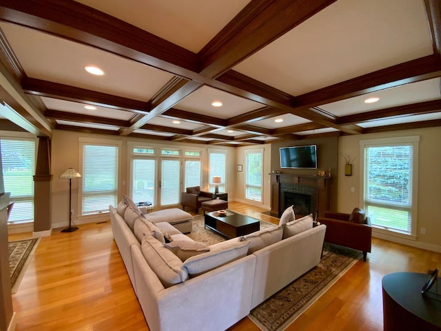 living area with light wood-style floors, plenty of natural light, a fireplace, and beam ceiling