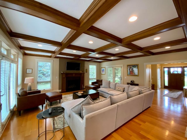 living room with light wood-type flooring, beamed ceiling, coffered ceiling, and a fireplace