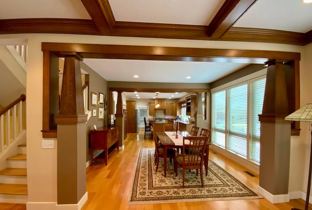 dining space with light hardwood / wood-style floors, ornate columns, and beam ceiling